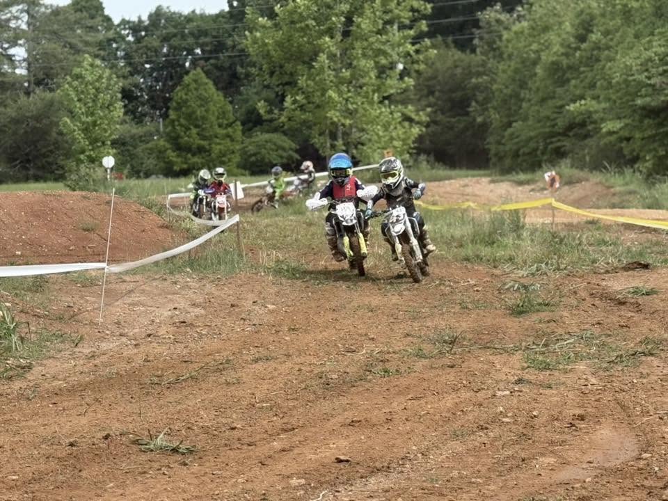 Helmeted dirt-bike riders racing on a dirt course